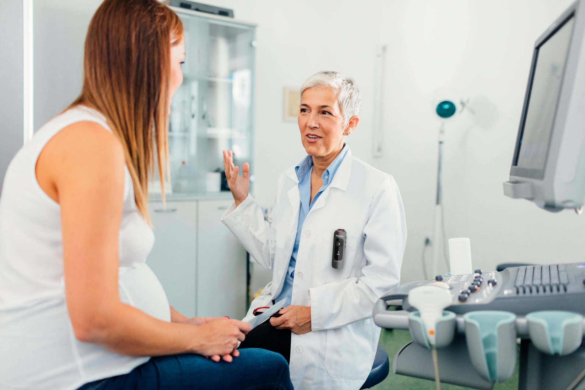 Physician wearing a Philips SpeechMike Ambient performing prenatal ultrasound imaging